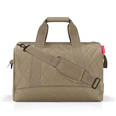 A tan quilted duffel bag with tan straps and black hardware is shown against a white background.