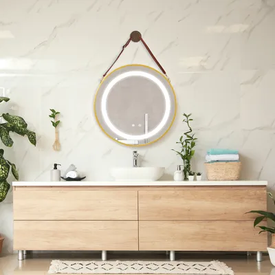 A modern bathroom vanity with a round LED mirror, sink, and plants.