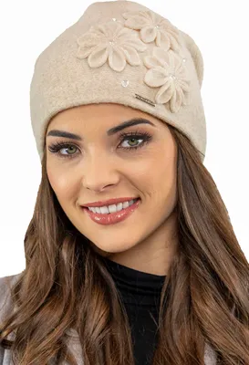A woman wearing a beige winter hat with flower appliqués.