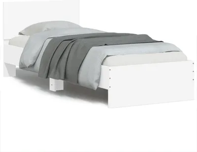 A white bed frame with a mattress and bedding, shown from a side angle.