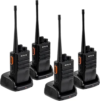 Four black walkie-talkies with orange accents are shown in their charging docks against a white background.