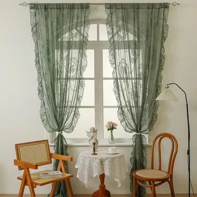A room interior with a window dressed with green lace curtains, a small round table with a figurine and a teacup, and two chairs.