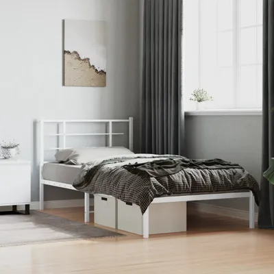 A white metal bed frame with bedding and storage boxes underneath, shown in a bedroom setting.