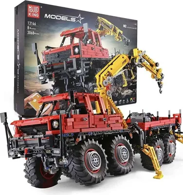 A red and yellow construction vehicle toy model with a crane, displayed in front of its packaging.