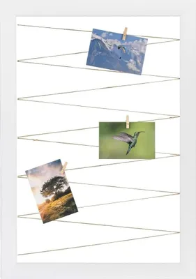 A white picture frame with string and clothespins holding up three photographs.