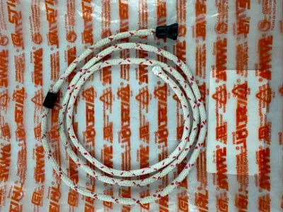 A starter rope and a small white paper product are laid out on a white background with a repeating orange STIHL logo pattern.