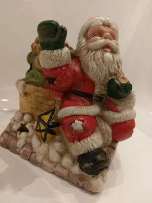 Nikolaus als Keramik-Windlicht, der aus einem Kamin klettert und einen Sack mit Geschenken trägt.