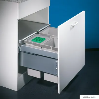 A white kitchen cabinet with a pull-out drawer containing two trash bins and a green divider.