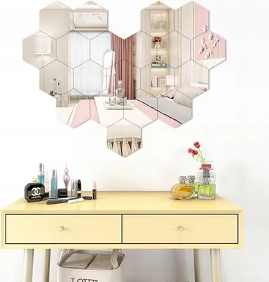 A vanity table with makeup and perfume, with a hexagonal mirror arrangement on the wall above it.