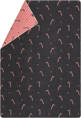 A folded blanket with a candy cane pattern on a dark background and a striped pattern on the inside.