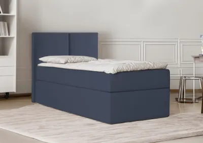 A dark blue bed with a white duvet and pillow is shown in a room with white paneled walls and a light-colored rug.