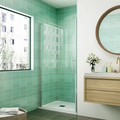 A modern bathroom with a green tiled shower enclosure and a wooden vanity.