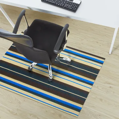 An office chair on a striped floor mat in front of a desk.