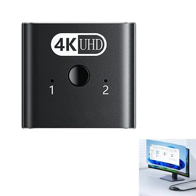 A black HDMI splitter with '4K UHD' branding and two input indicators labeled '1' and '2'. A smaller inset image shows a computer monitor displaying a Windows interface.
