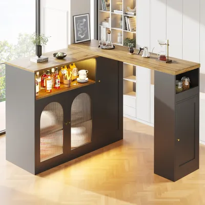 A modern bar counter with bottles of alcohol and glassware displayed on top, and cabinets below with glass doors.