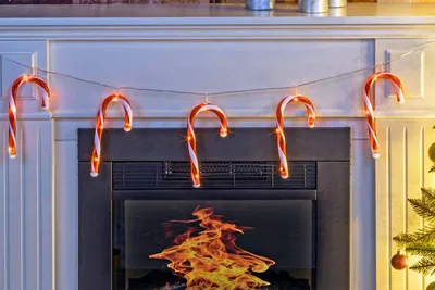 A string of candy cane-shaped lights hangs above a fireplace.