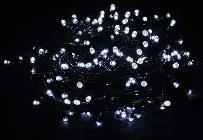 A tangled pile of white LED string lights on a black background.