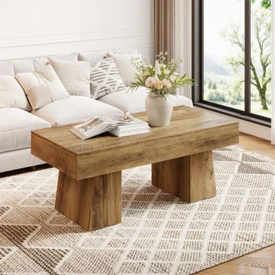 A living room scene with a couch, coffee table, and a large window with a view of trees.