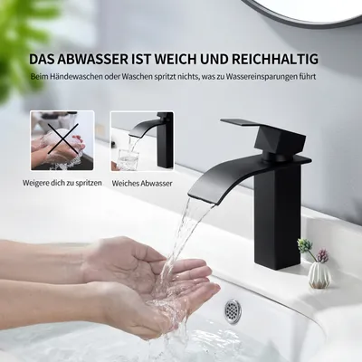 A black waterfall faucet in a bathroom sink with hands washing under the water.