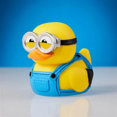 A yellow rubber duck with Minion-like goggles and blue overalls against a blue background.