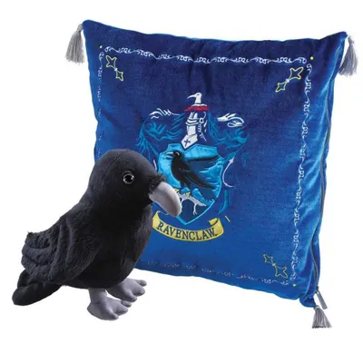 A plush raven toy sits next to a blue cushion with the Ravenclaw crest from Harry Potter.