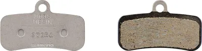 Two bicycle brake pads shown against a white background. One pad shows the metal backing with embossed text, and the other shows the friction material.