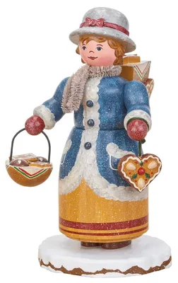 Zu sehen ist eine detailreich gestaltete Räucherfigur in traditioneller Kleidung die eine Lebkuchenhändlerin darstellt und in den Händen einen Korb mit Lebkuchen sowie ein Lebkuchenherz hält während sie auf einem schneebedeckten Sockel steht