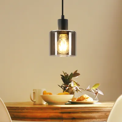 A pendant light hangs above a dining table set with a bowl of fruit and croissants.