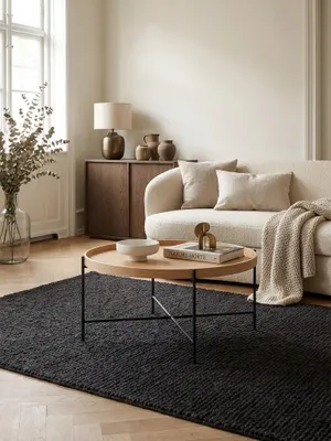 Runder Couchtisch aus Eichenholz mit filigranem Metallgestell als Mittelpunkt einer stilvollen Wohnzimmer-Sitzgruppe auf einem dunklen Teppich vor einem Sofa._#sku_SAFWL6.493#