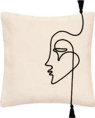 A cream-colored throw pillow with a black abstract face design and tassels.