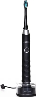 A black electric toothbrush with a blue-tipped brush head sits in its charging base.