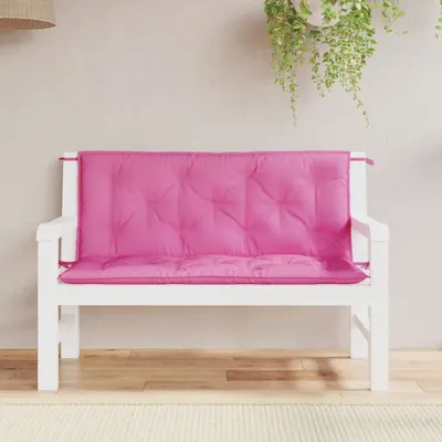 A pink cushion on a white bench in an outdoor setting.