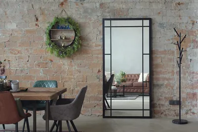 A dining area with a mirror, chairs, and a table against a brick wall.