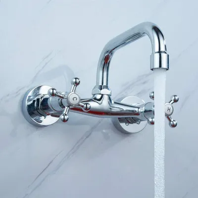 A chrome-plated wall-mounted faucet with two handles, one marked 'C' and the other 'H', is shown with water flowing from the spout.