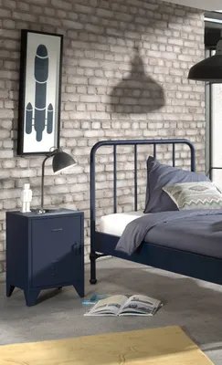 A bedroom scene with a bed, nightstand, and artwork on the wall.