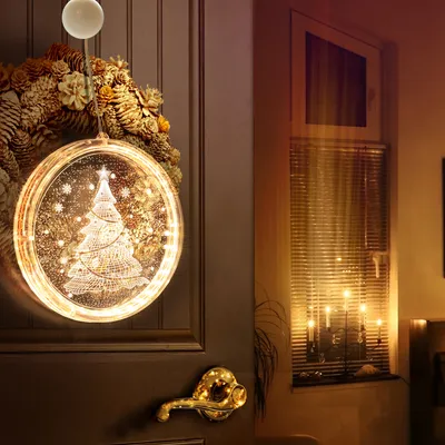 A festive Christmas decoration hangs on a door, with a window and candles visible in the background.