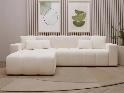 A cream-colored sectional sofa is shown in a well-lit room with modern art on the wall.