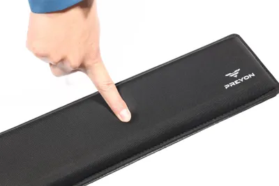 A hand is pressing down on a black wrist rest.