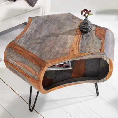A unique, organically shaped coffee table made of wood with a storage compartment and hairpin legs, placed on a light wooden floor.