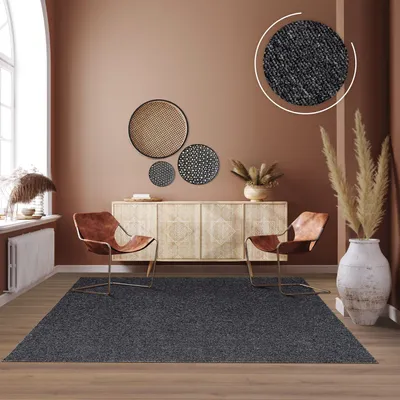 A modern living room with a rug, chairs, and a sideboard.