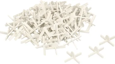 A pile of white tile spacers with a few individual spacers in the foreground.