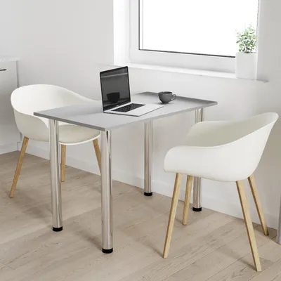 A modern dining set with a light graphite table and two white chairs, placed near a window.