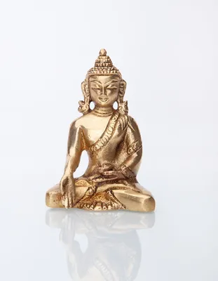 A golden Buddha statue sits in a meditative pose on a reflective white surface.
