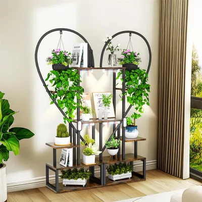 A heart-shaped plant stand with multiple shelves, filled with various plants and books, placed indoors near a window.