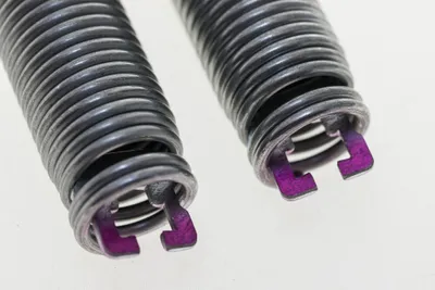 Close-up of two garage door springs with purple accents.