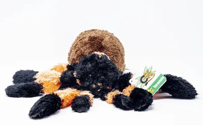 A plush toy tarantula is lying on a white background.
