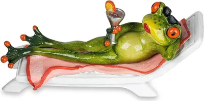 A ceramic figurine of a frog relaxing on a lounge chair with a drink.