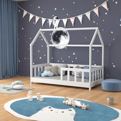 A child's bedroom with a house-shaped bed, decorated with stars and a moon lamp.