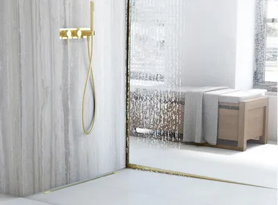 A modern bathroom with a gold shower fixture and a textured glass shower door.
