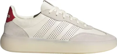 A side view of a white Adidas sneaker with red accents.